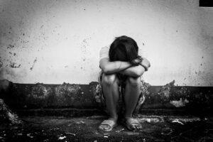 Photo of crying child sitting against a wall