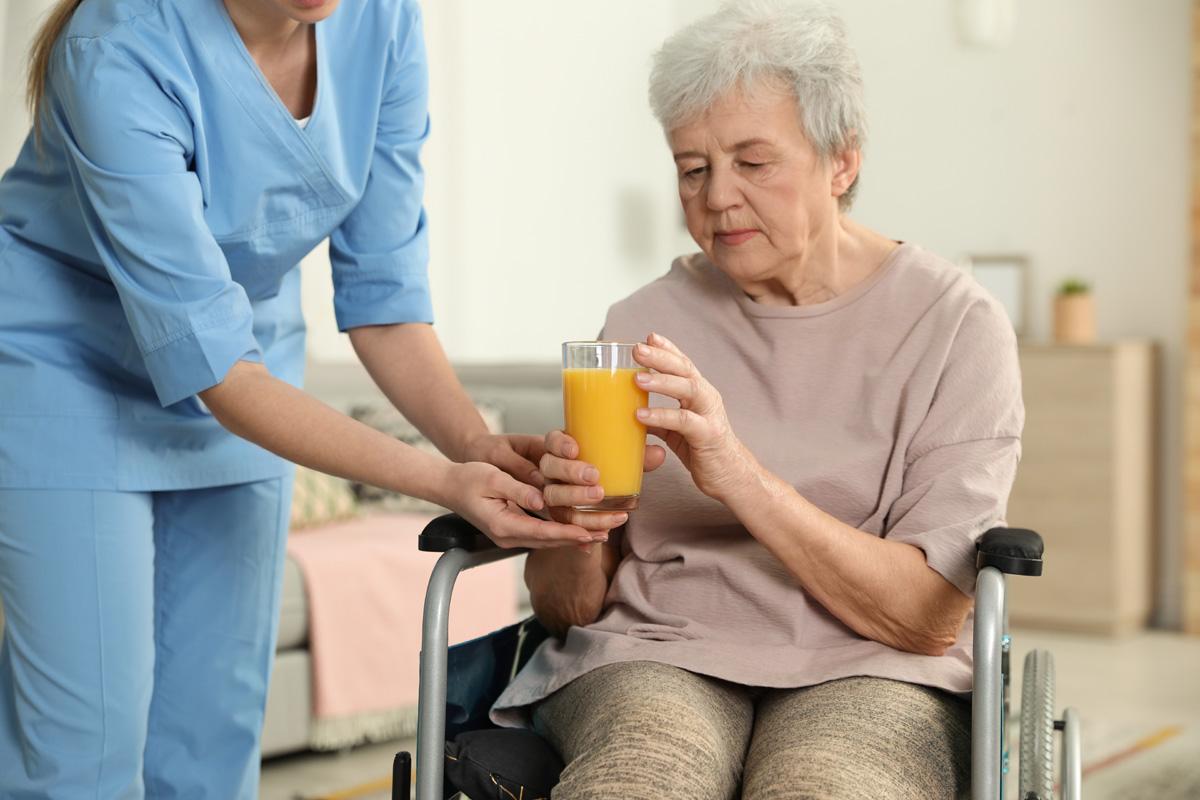 Nurse-giving-glass-of-juice-to-elderly-woman