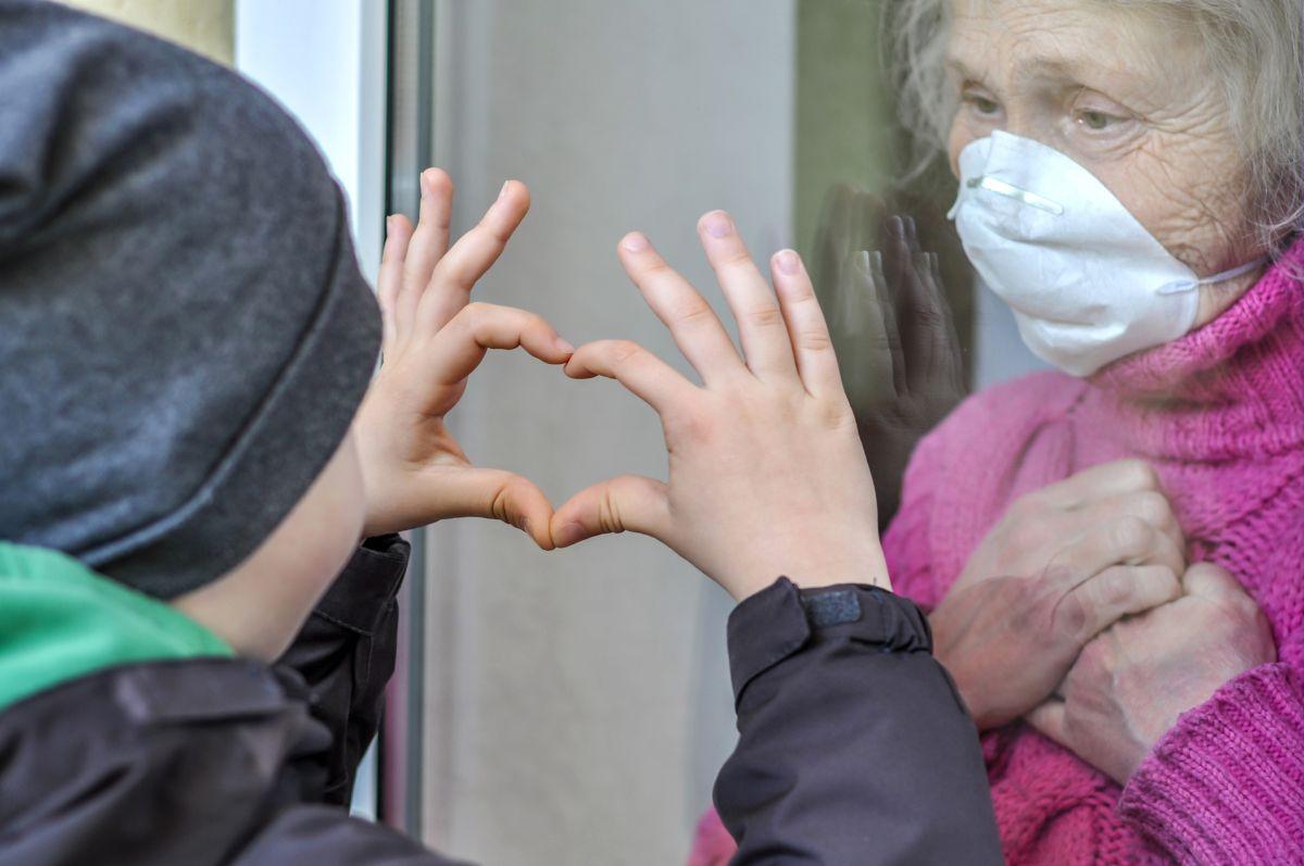 Boy visits his grandmother from outside a window during COVID-19 pandemic