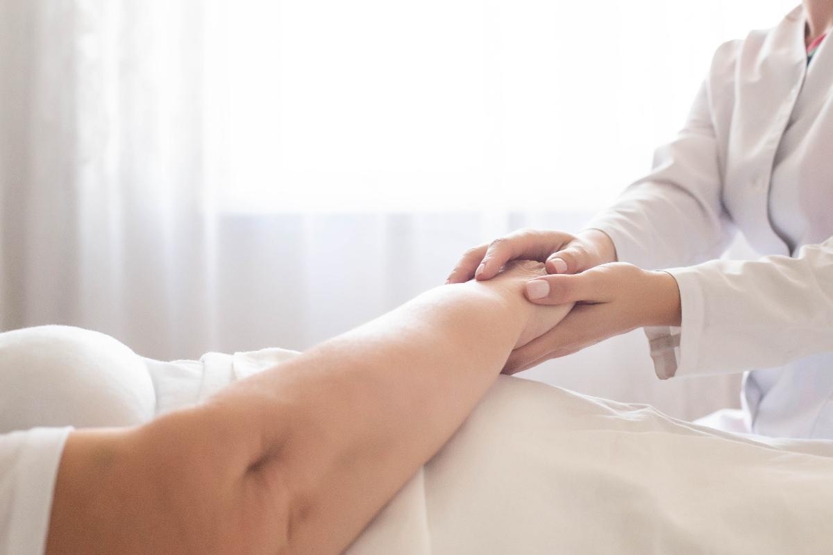 Nurse comforting elderly patient on hospital bed. The complications that may arise from bedsores in nursing homes.