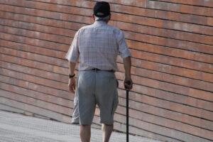 Elderly man with cane wandering the city.