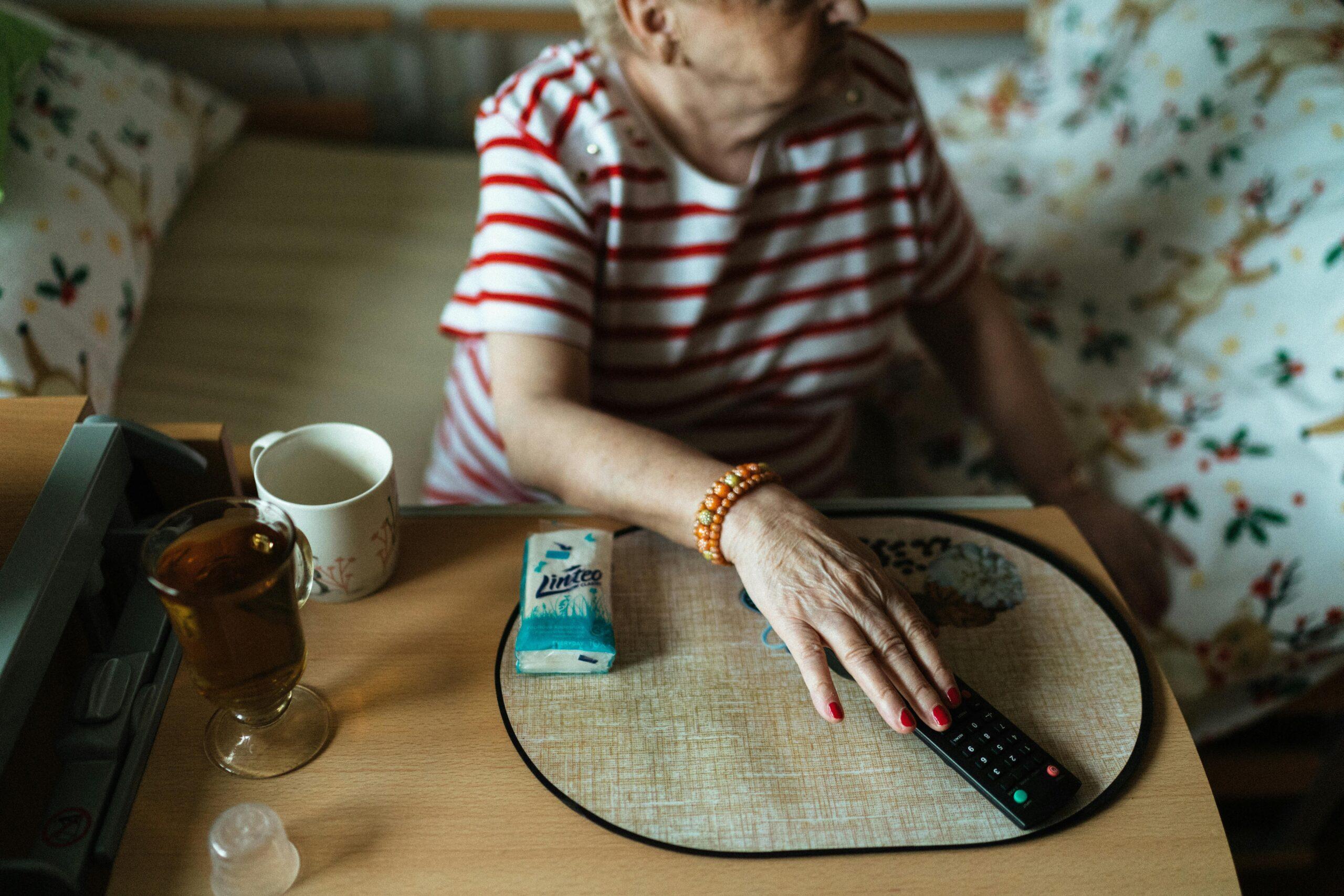 elderly woman holding a tv remote
