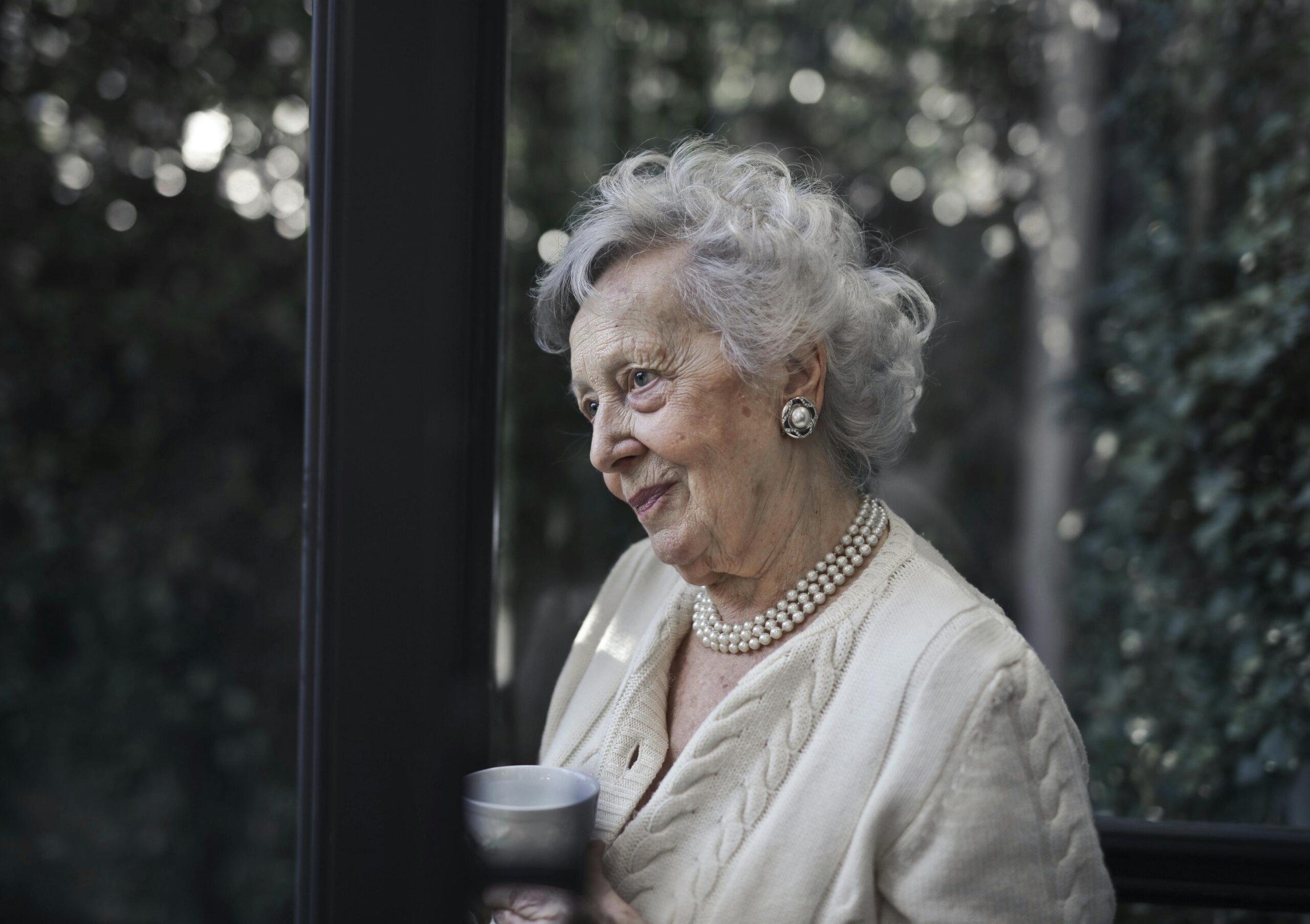elderly woman looking through the window
