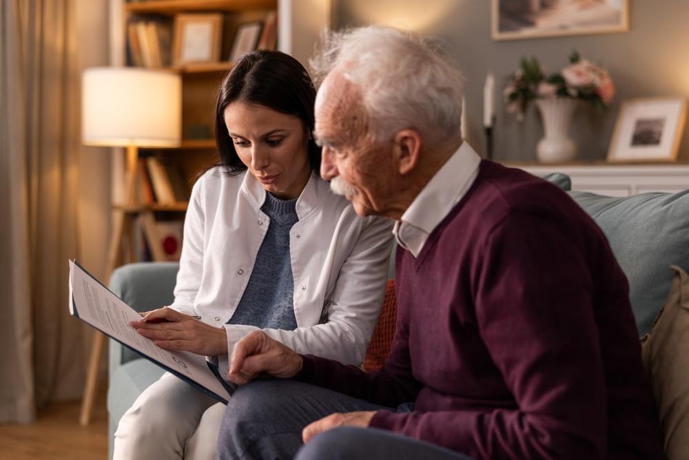 Woman and an older man sitting on a couch reviewing a document together